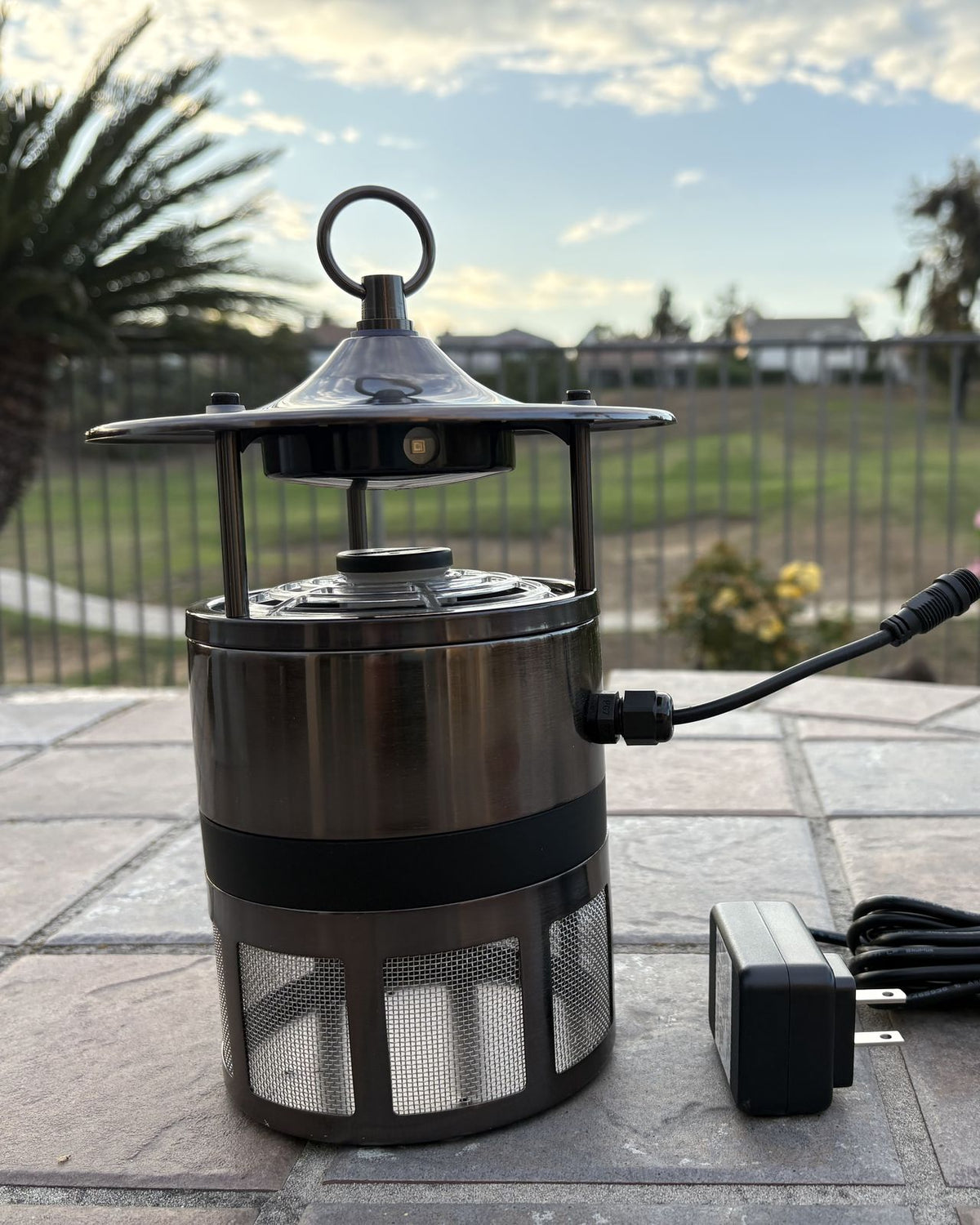 MM400 stainless steel mosquito trap on a patio with its power adapter