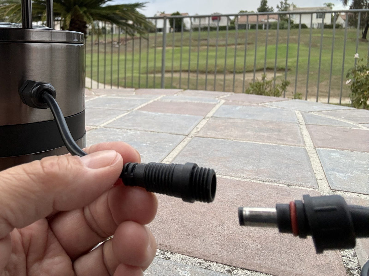 Hand holding the MM400's screw-lock power connector, both ends